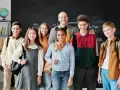 Uśmiechnięty nauczyciel i uczniowie przed tablicą. Czy szkoła społeczna to miejsce, gdzie tak dobrze się czują?
