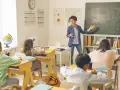 Nauczycielka tłumaczy zadanie z fizyki przy tablicy, dzieląc się wiedzą i doświadczeniem z uczniami.