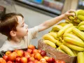 Chłopiec sięga po banana, a jego spojrzenie zdradza psychologię dziecka kradnącego słodkości.