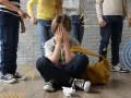 Dziecko zakrywa twarz, otoczone przez inne dzieci, które wskazują palcami. To obraz tego, czym jest bullying.