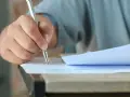 Dłoń trzymająca długopis, która wypełnia test. Czy przed jak również stawiamy przecinek, gdy piszemy.