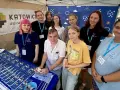 Grupa młodych ludzi i dorosłych prezentuje materiały promocyjne liceum online dla młodzieży.