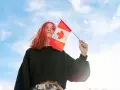 Dziewczyna z kolorowymi włosami trzyma flagę Kanady. Może to być symbol jej miłości do kraju lub wspomnienie z pobytu w szkole w Kanadzie.