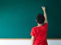 Chłopiec pisze kredą na tablicy, zastanawiając się, przed jakimi spójnikami stawiamy przecinek.