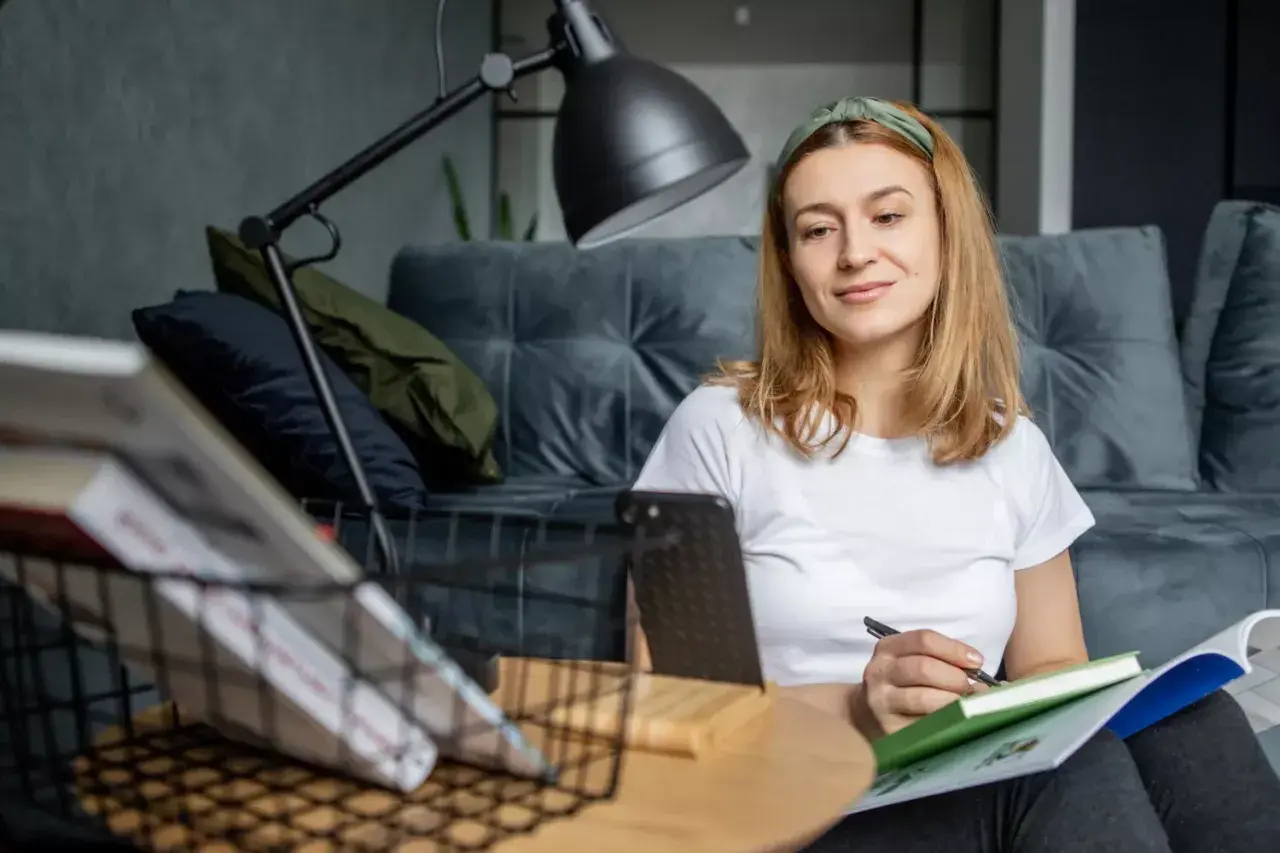 Kto może uczyć wosu w szkole podstawowej? Młoda kobieta z zeszytem i długopisem, przygotowująca się do lekcji.