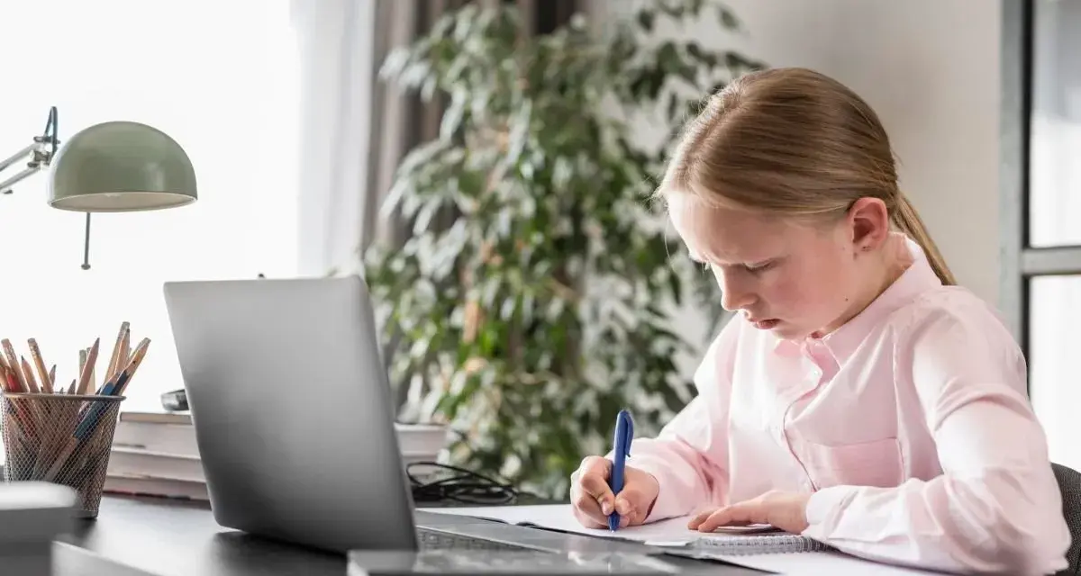 Dziewczynka uczy się w domu, pisząc w zeszycie. Czy nauczanie domowe jest płatne?