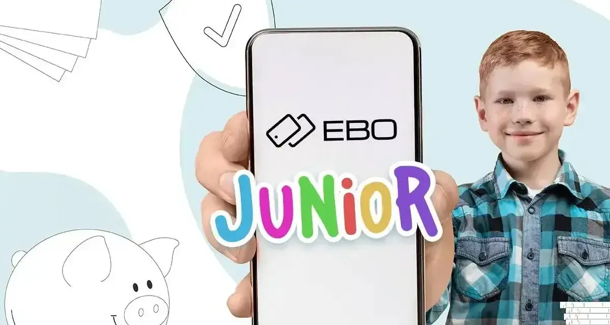 Chłopiec z uśmiechem trzyma telefon z napisem EBO Junior. Obok świnka skarbonka i stos banknotów. Idealne rozwiązanie na kieszonkowe dla 18 latka.