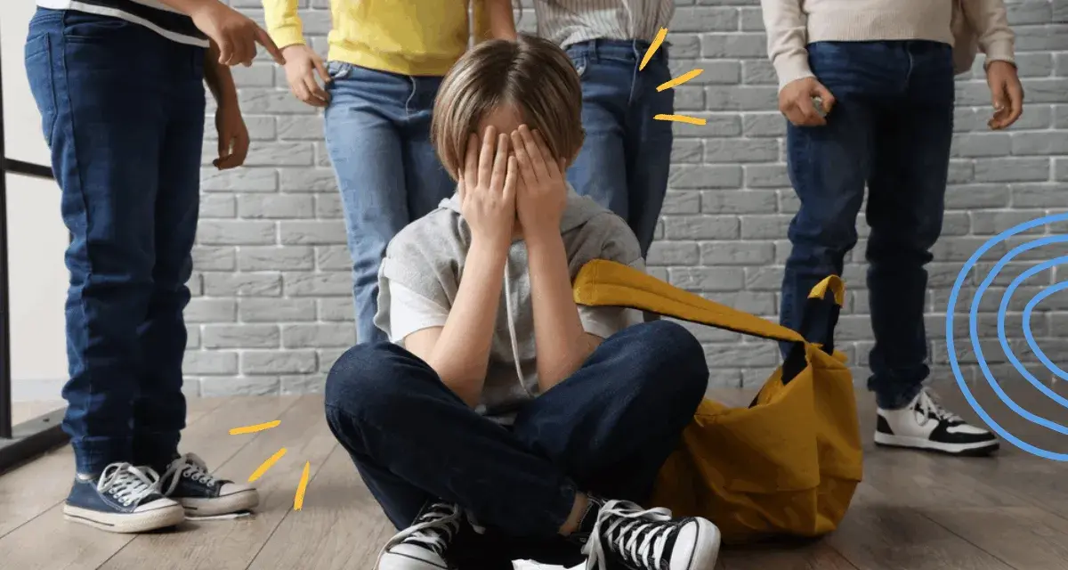 Dziecko zakrywa twarz, otoczone przez inne dzieci, które wskazują palcami. To obraz tego, czym jest bullying.