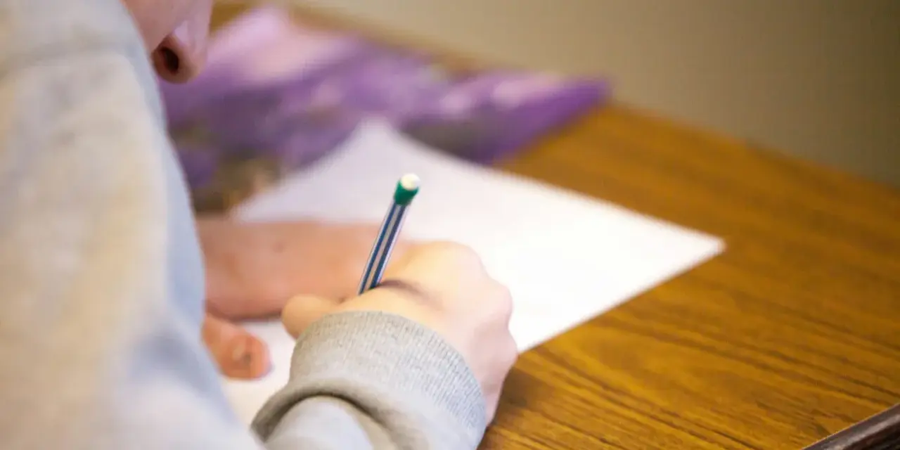 Uczeń pisze test maturalny, skupiony na zadaniu. Szkoła w chmurze matura to przyszłość edukacji.