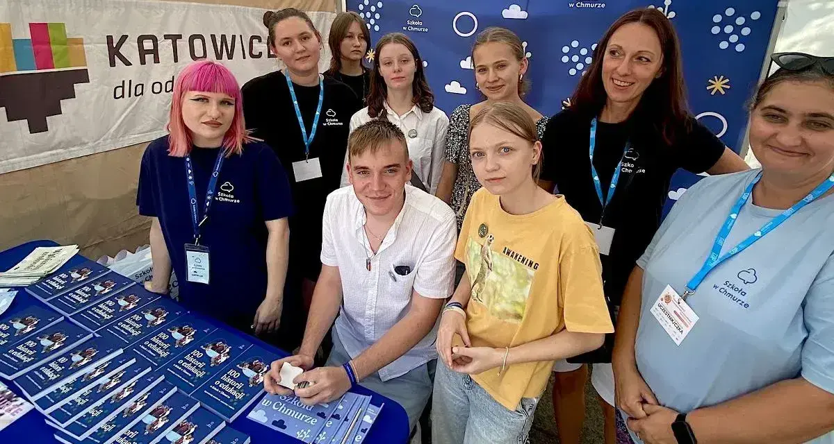 Grupa młodych ludzi i dorosłych prezentuje materiały promocyjne liceum online dla młodzieży.