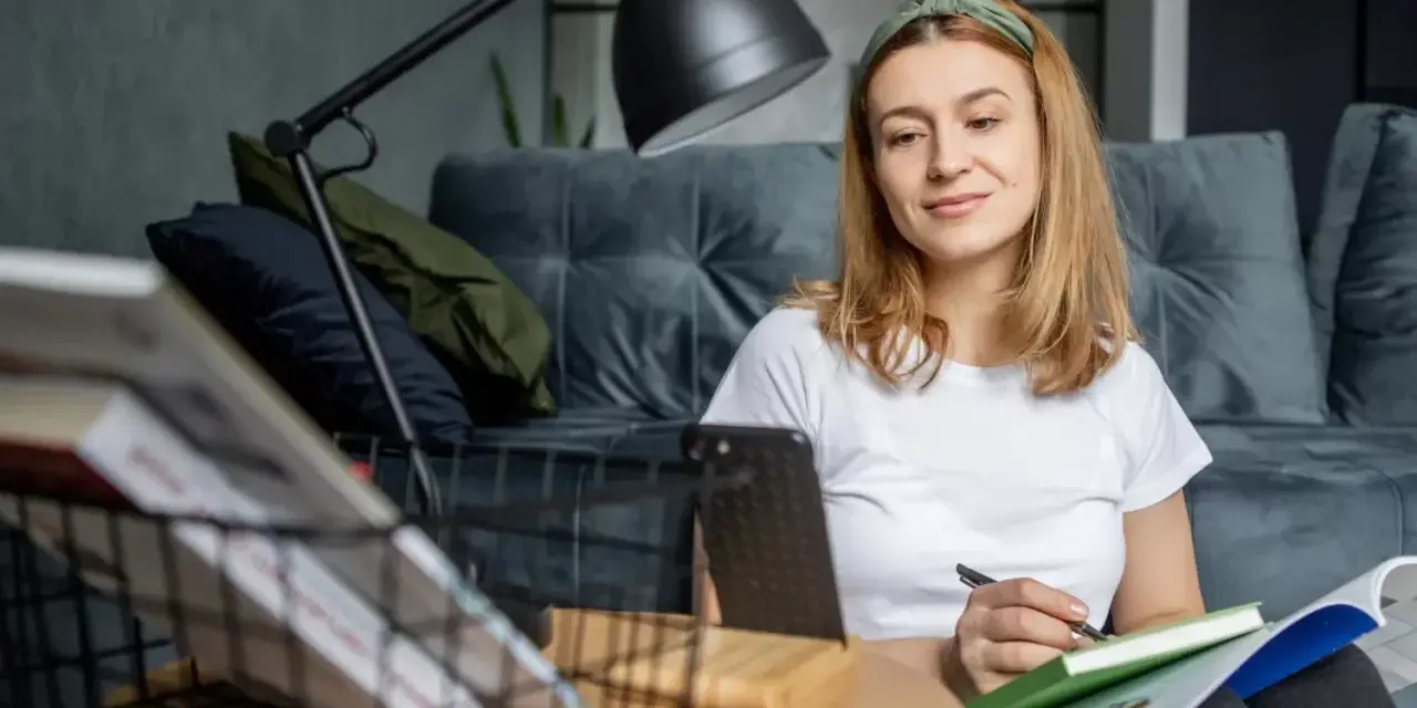 Kto może uczyć wosu w szkole podstawowej? Młoda kobieta z zeszytem i długopisem, przygotowująca się do lekcji.