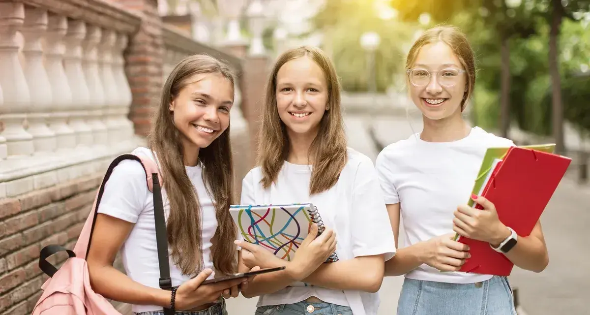 Trzy uśmiechnięte uczennice z zeszytami i teczkami. Czy w 7 klasie jest plastyka? Pewnie tak, skoro mają tyle materiałów!