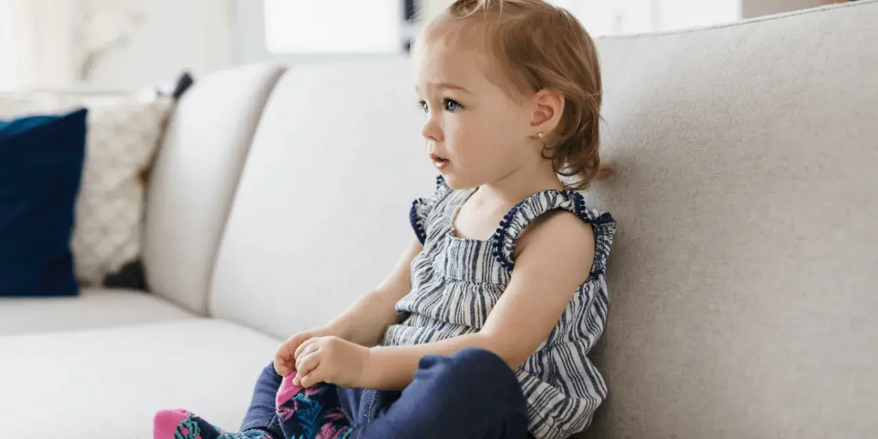 Mała dziewczynka siedzi na kanapie, wyrażając różne emocje, jak w filmie edukacyjnym dla dzieci.