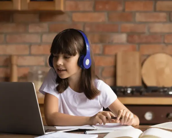 Dziewczynka w słuchawkach uczy się z laptopem. Jej liceum online to przyszłość edukacji.