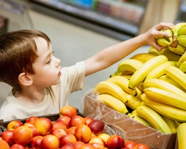 Chłopiec sięga po banana, a jego spojrzenie zdradza psychologię dziecka kradnącego słodkości.