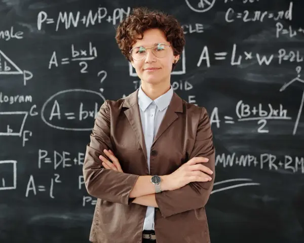 Nauczycielka z okularami na tle tablicy z równaniami matematycznymi. To obraz edukacji w Norwegii, gdzie nauka jest priorytetem.