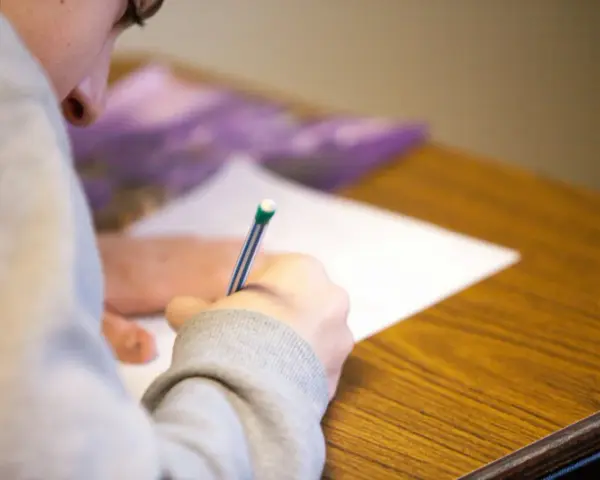 Uczeń pisze test maturalny, skupiony na zadaniu. Szkoła w chmurze matura to przyszłość edukacji.