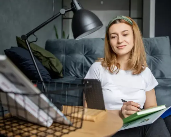Kto może uczyć wosu w szkole podstawowej? Młoda kobieta z zeszytem i długopisem, przygotowująca się do lekcji.