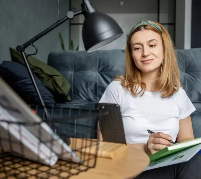 Kto może uczyć wosu w szkole podstawowej? Młoda kobieta z zeszytem i długopisem, przygotowująca się do lekcji.