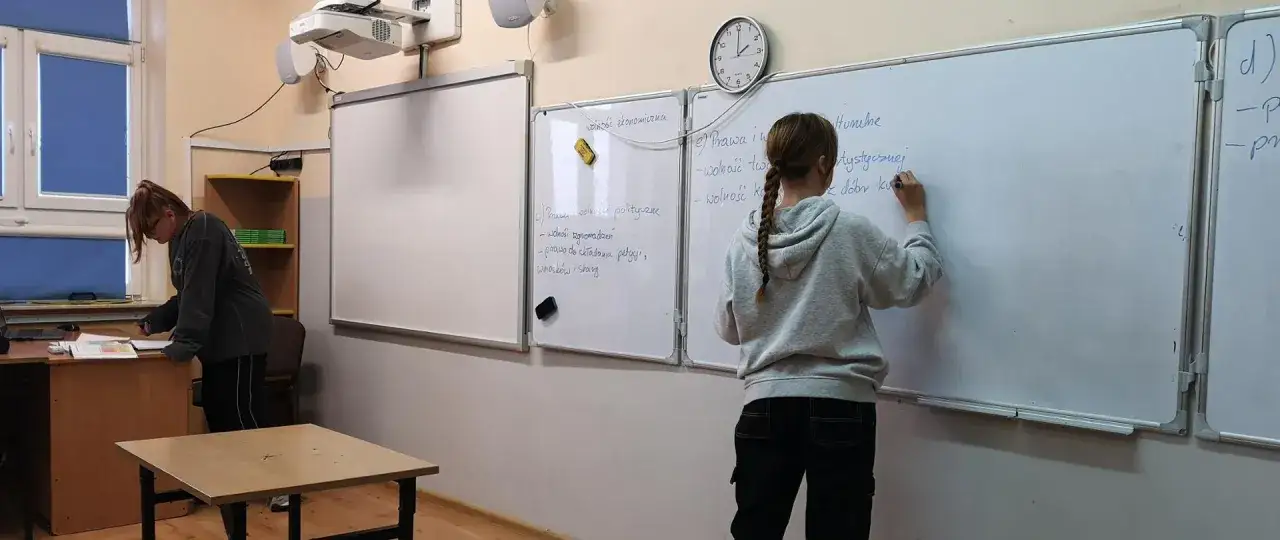 Uczennica pisze na tablicy o prawach i wolnościach. Kto może uczyć wosu w szkole podstawowej? Nauczyciel z odpowiednimi kwalifikacjami.