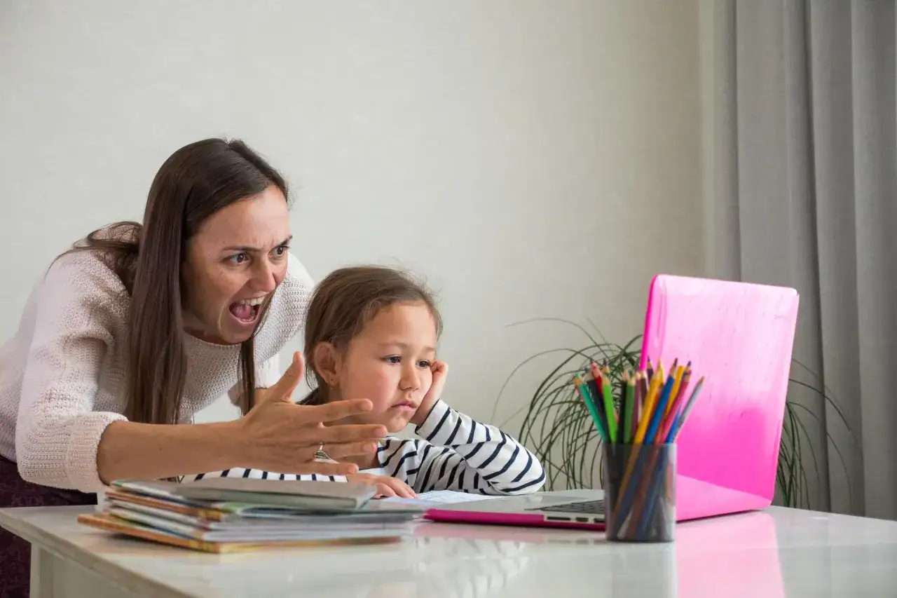 Zestresowana mama krzyczy na 5-letnie dziecko, które boi się wszystkiego, siedząc przy laptopie.