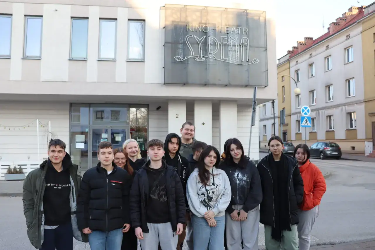 Grupa młodzieży przed kinem-teatrem Syrena. Może to być kadr z filmu na lekcję wychowawczą, pokazujący wspólne wyjście na seans.